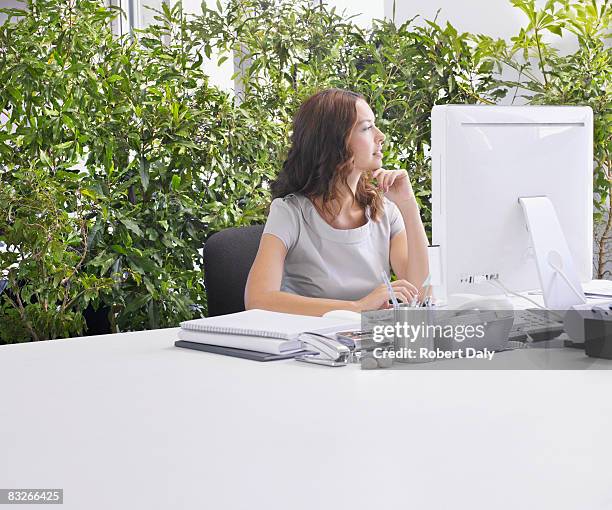 businesswoman at desk surrounded by plants - person surrounded by computer screens stock pictures, royalty-free photos & images