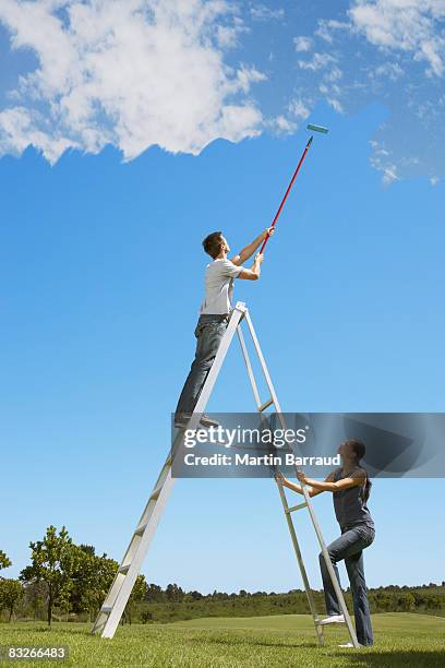 couple painting the sky blue - woman on ladder painting stock pictures, royalty-free photos & images