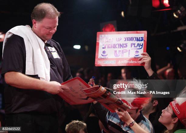 Raymond van Barneveld of the Netherlands signs autographs for England's Andy Jenkins fans after winning their Semi-final match 6-0 in the World Darts...