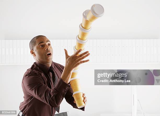 businessman unsuccessfully balancing large stack of paper coffee cups - take away coffee cup stock pictures, royalty-free photos & images