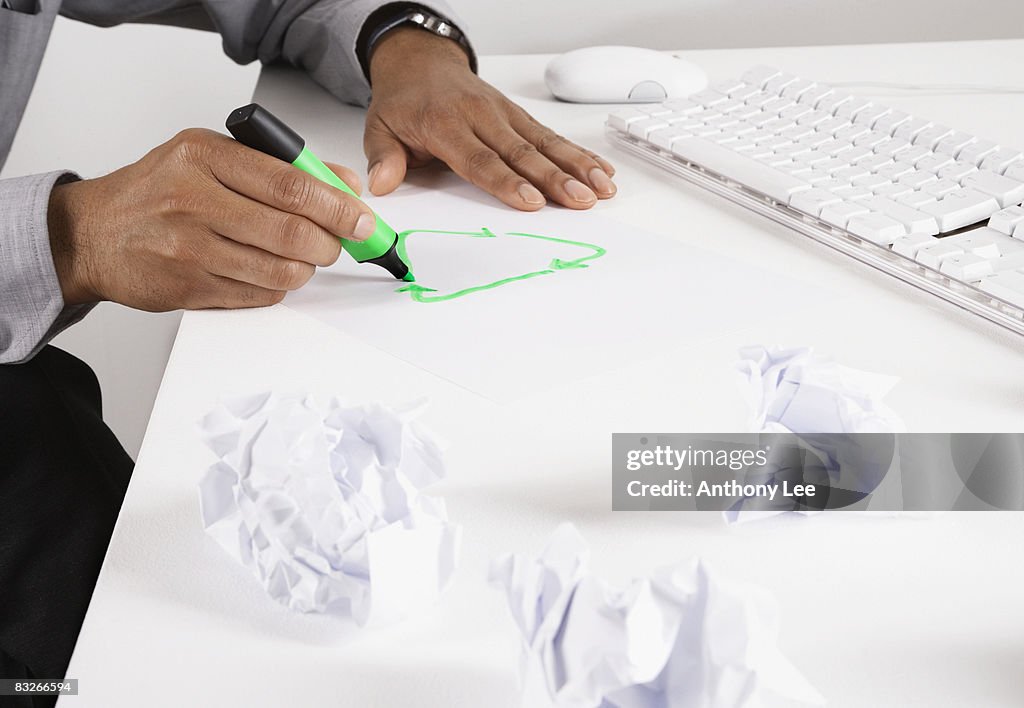 Businessman drawing recycling symbol on desk with marker