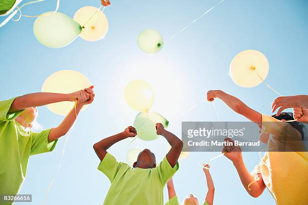 group of children holding balloons outdoors - releasing stock pictures, royalty-free photos & images