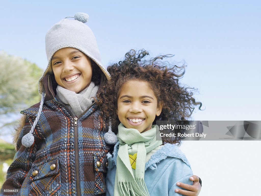 Two young sisters hugging in winter