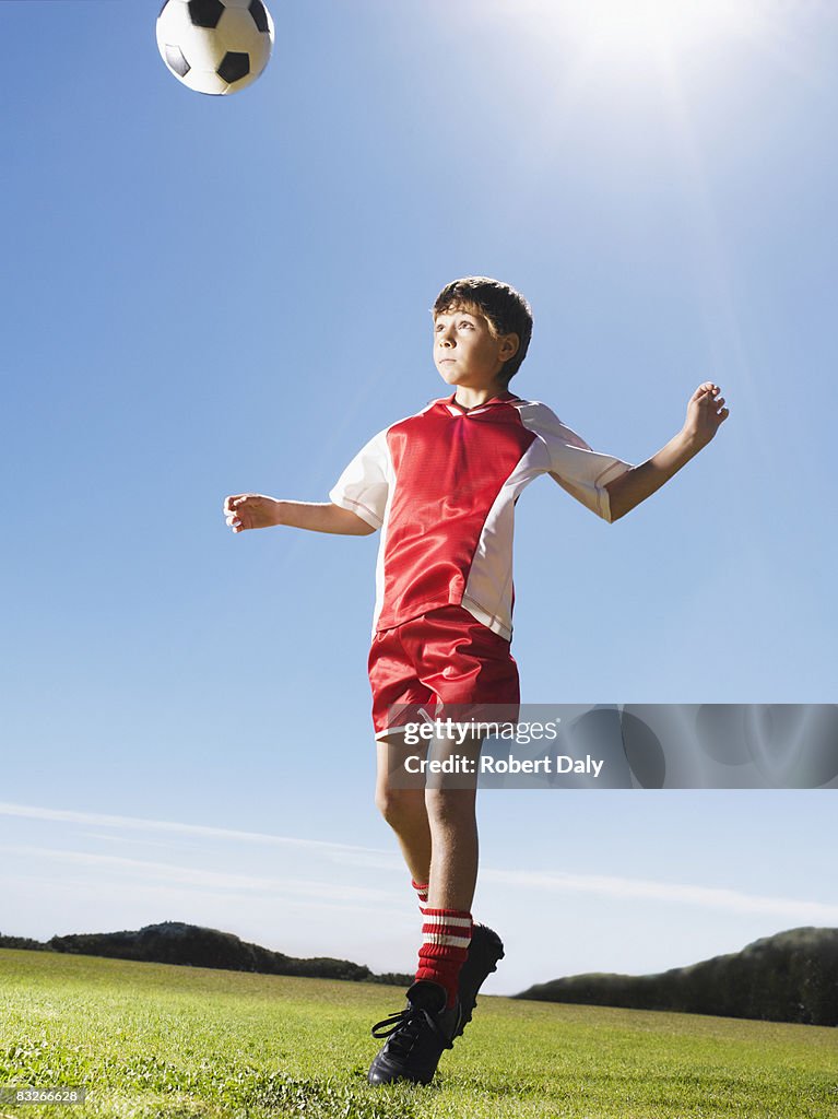 Young boy in uniform heading soccer ball