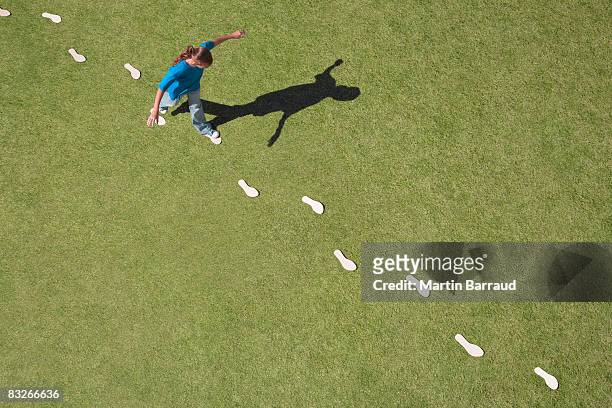 young girl following footprints on grass - footprint stock pictures, royalty-free photos & images