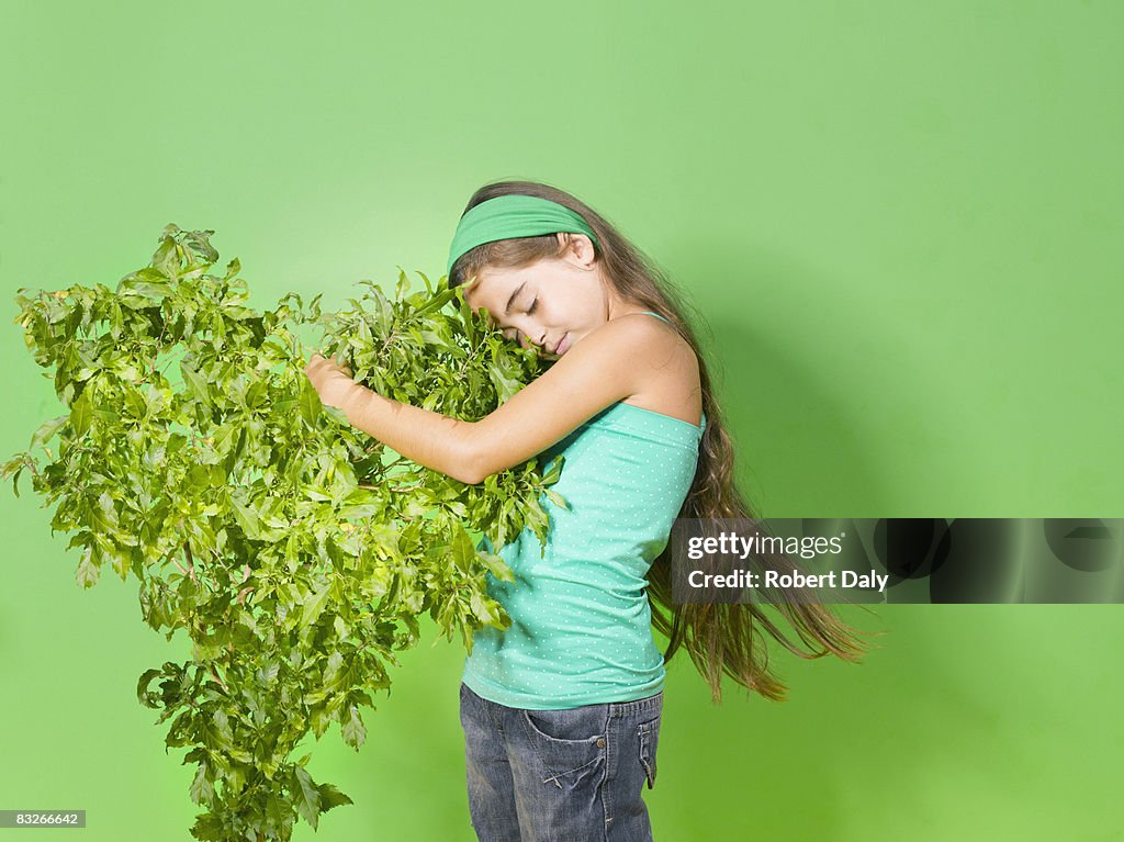 Menina abraçando verde bush