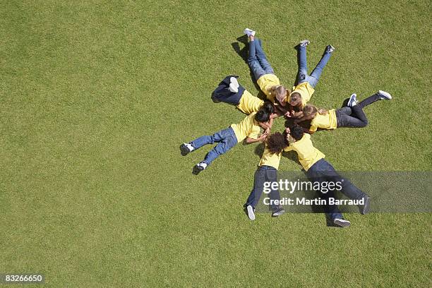 groupe d'enfants, allongé sur l'herbe dans un cercle de formation - allongé sur le devant photos et images de collection