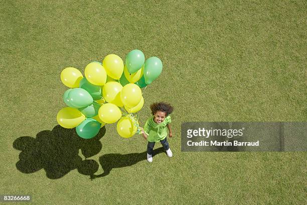 young girl holding bunch of balloons - releasing stock pictures, royalty-free photos & images