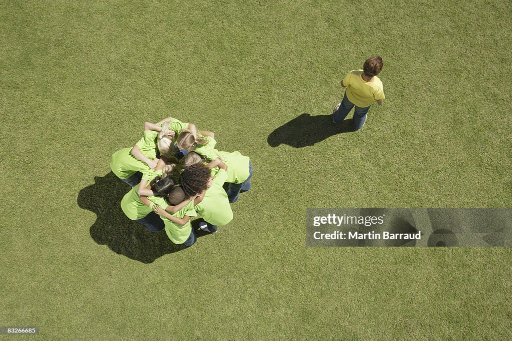 Group of children in huddle with one boy excluded