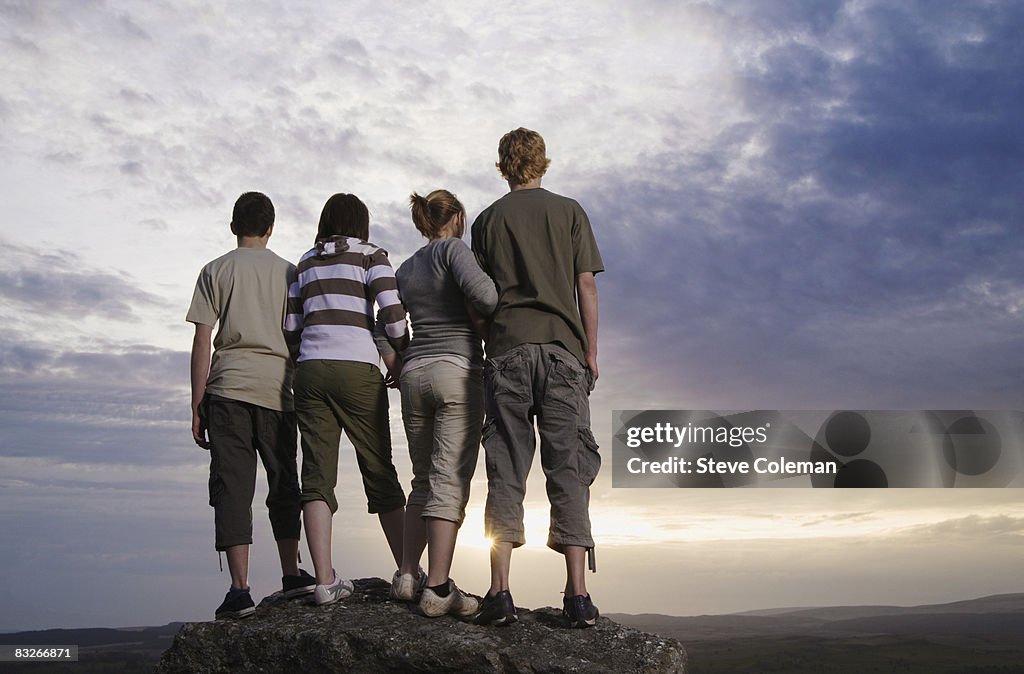 Teenage friends standing on rock viewing countryside