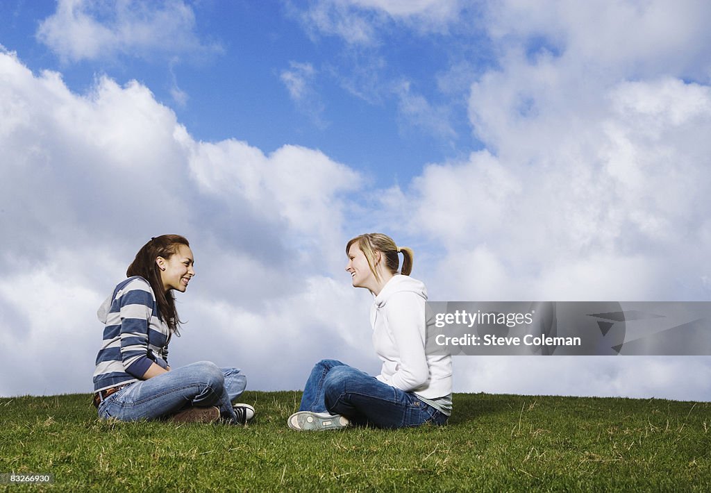 Teenage girls sitting in grass talking