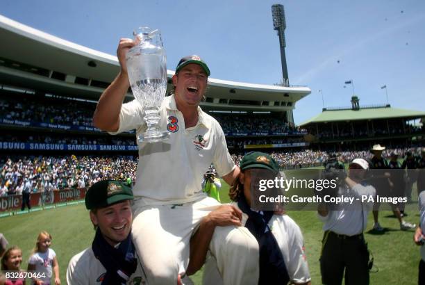 Australia's Shane Warne is carried around the field with the official Ashes Trophy by Michael Clarke and Andrew Symonds after defeating England on...