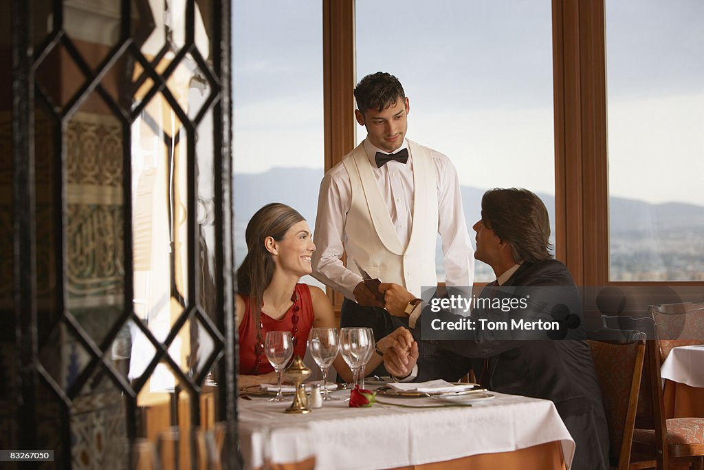 Waiter serving couple in elegant restaurant