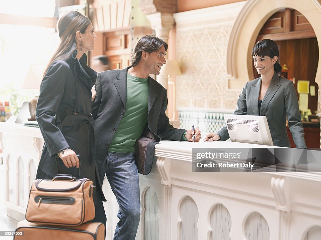 Hotel receptionist checking couple in