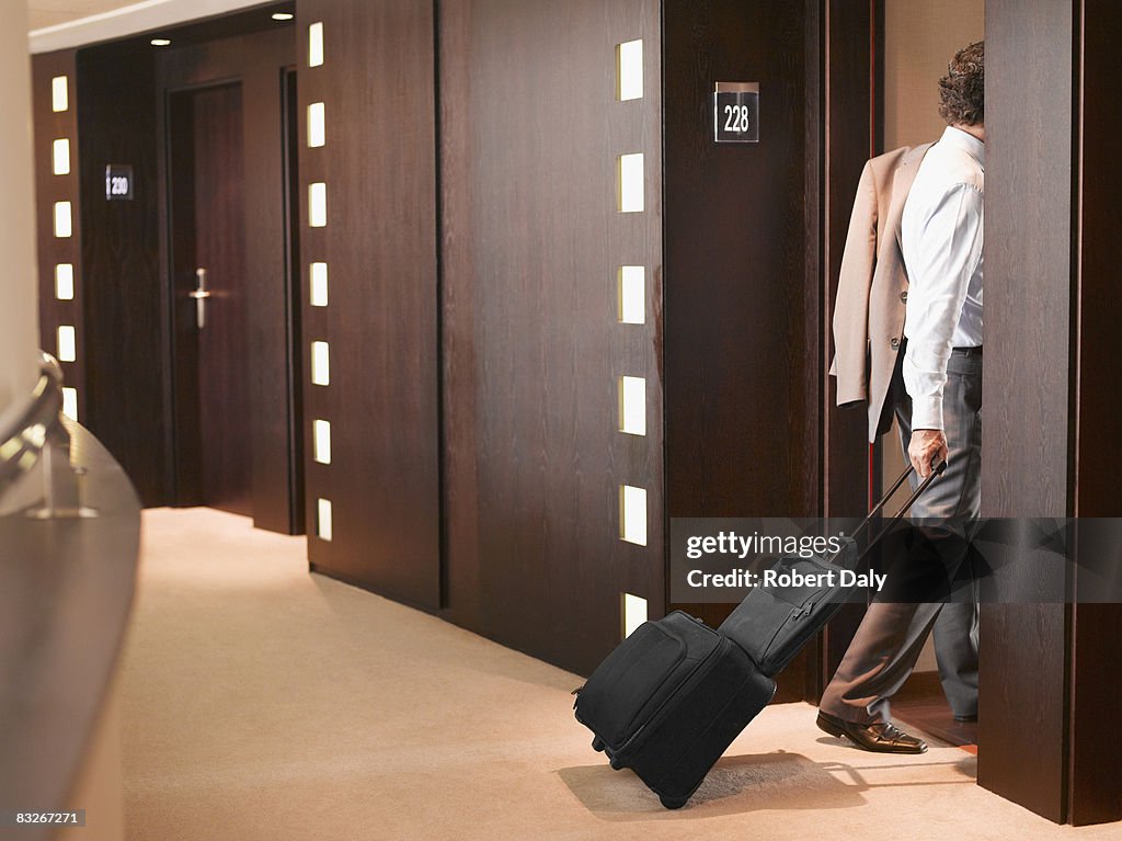 Businessman entering hotel room with suitcase