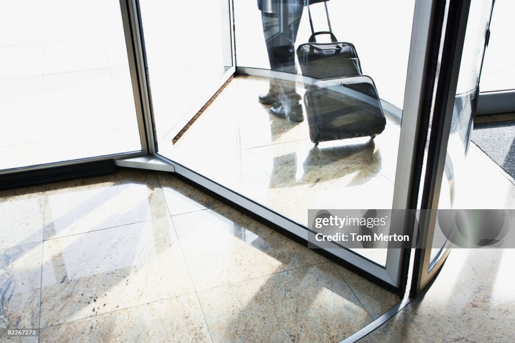 Businessman with suitcase using revolving door