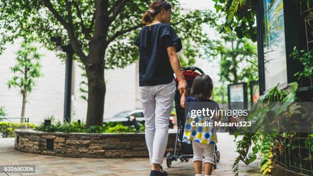 都市公園を歩いて母と赤ちゃんの女の子の後姿 - ベビーカー ストックフォトと画像