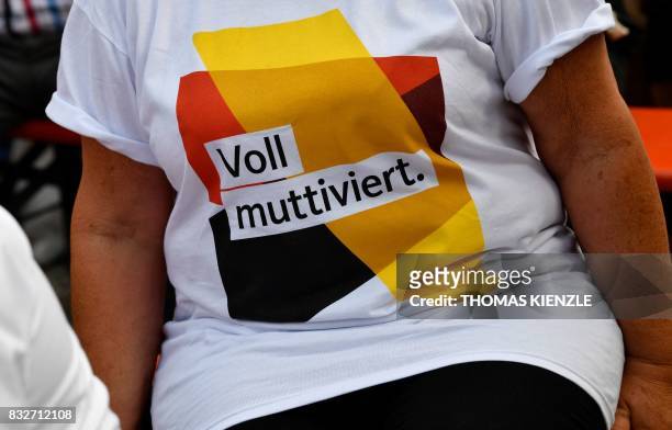 Supporter of German Chancellor Angela Merkel wears a t-shirt in the German colours which reads "Full Motivated" spelt with a play on words using...