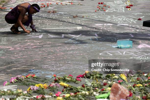 Woman leaves a message in chalk on the street where Heather Heyer was killed and 19 others injured when a car slammed into a crowd of people...