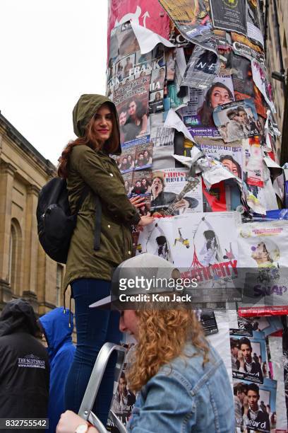Young woman posts promotional flyers on a pillar during the Edinburgh Festival Fringe, on August 16, 2017 in Edinburgh, Scotland. The Fringe is...