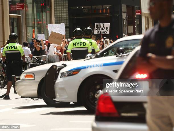 Police stand in front of protesters as President Donald Trump's motorcade departs Trump Tower on August 16, 2017 in New York City. Trump is traveling...