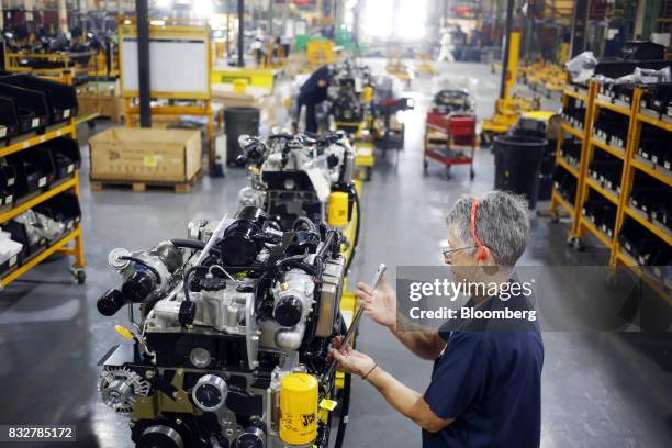 Worker assembles an engine for a skid steer loader construction vehicle at the JC Bamford Excavators LTD. Manufacturing plant in Pooler, Georgia,...