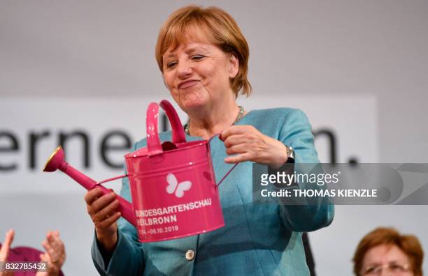 German Chancellor Angela Merkel holds a watering can she got as a gift during an election campaign rally of the Christian Democratic Union in...