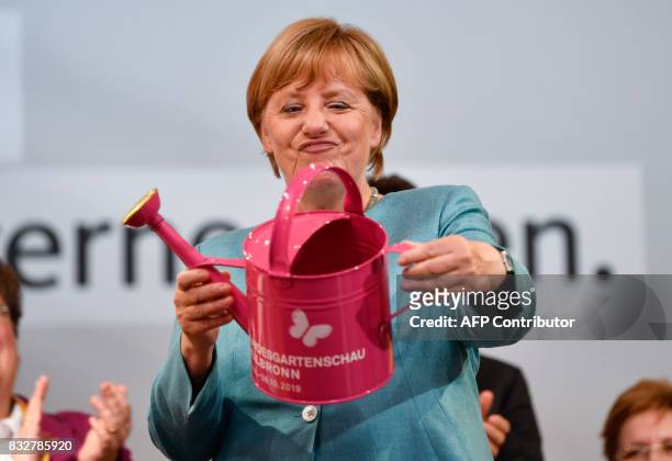 German Chancellor Angela Merkel holds a watering can she got as a gift during an election campaign rally of the Christian Democratic Union in...