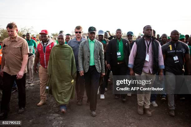 President of Association of Mineworkers and Construction Union Joseph Mathunjwa walks back with his private security guards and suvivors from the...