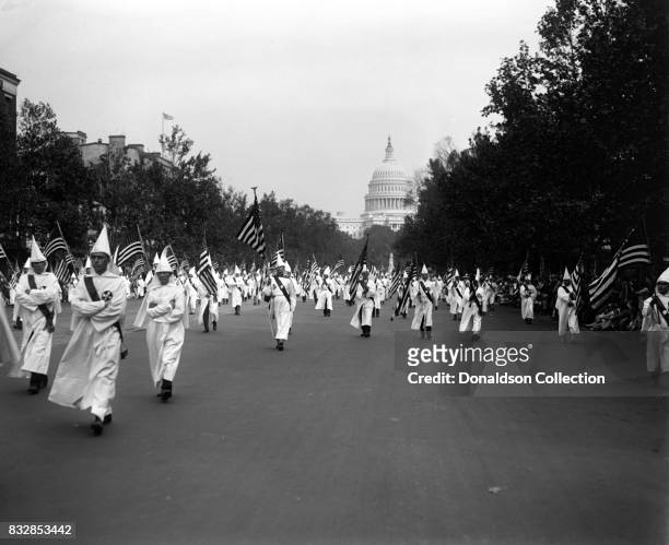 Members of the Ku Klux Klan wearing hooded robes march down the street with the Capitol building in the background in Washington, D.C. On September...
