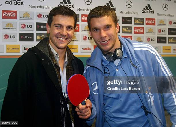 Table tennis player Timo Boll gives a racket to Lukas Podolski of Germany after the FIFA 2010 World Cup Qualifier match between Germany and Wales at...