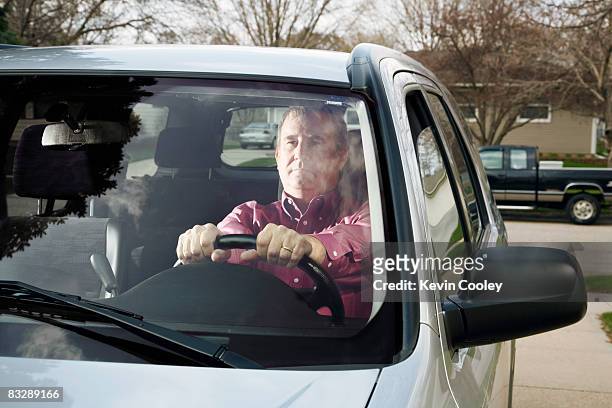 middle aged man thinking in car - car in driveway stock-fotos und bilder