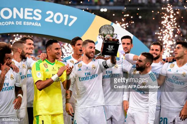 Real Madrid's defender Sergio Ramos holds up the trophy as he and teammates celebrate their Supercup after winning the second leg of the Spanish...