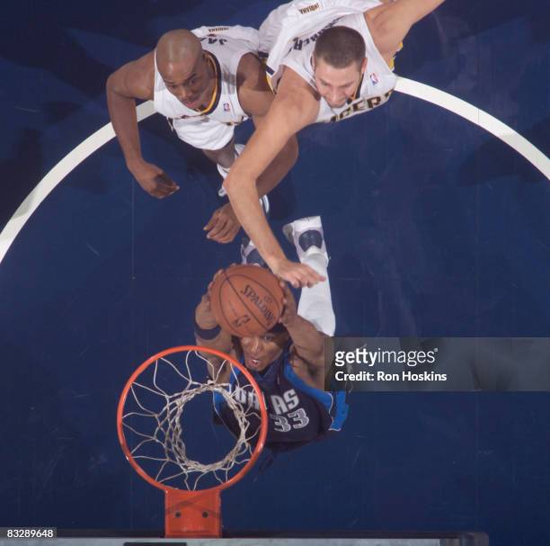 James Singleton of the Dallas Mavericks dunks over Jarrett Jack and Josh McRoberts of the Indiana Pacer at Conseco Fieldhouse on October 15, 2008 in...