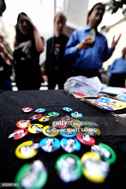 Supporters look at badges featuring pictures of Democratic presidential candidate Barack Obama kept for sale as they arrive to watch the televised...