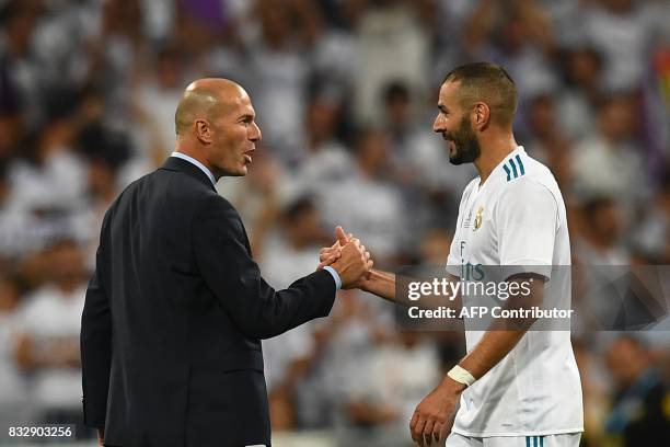 Real Madrid's French coach Zinedine Zidane and Real Madrid's French forward Karim Benzema congratulate each other as they celebrate their Supercup...