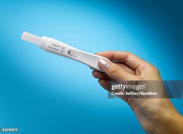 woman's hand holding pregnancy test  - pregnancy test stock pictures, royalty-free photos & images