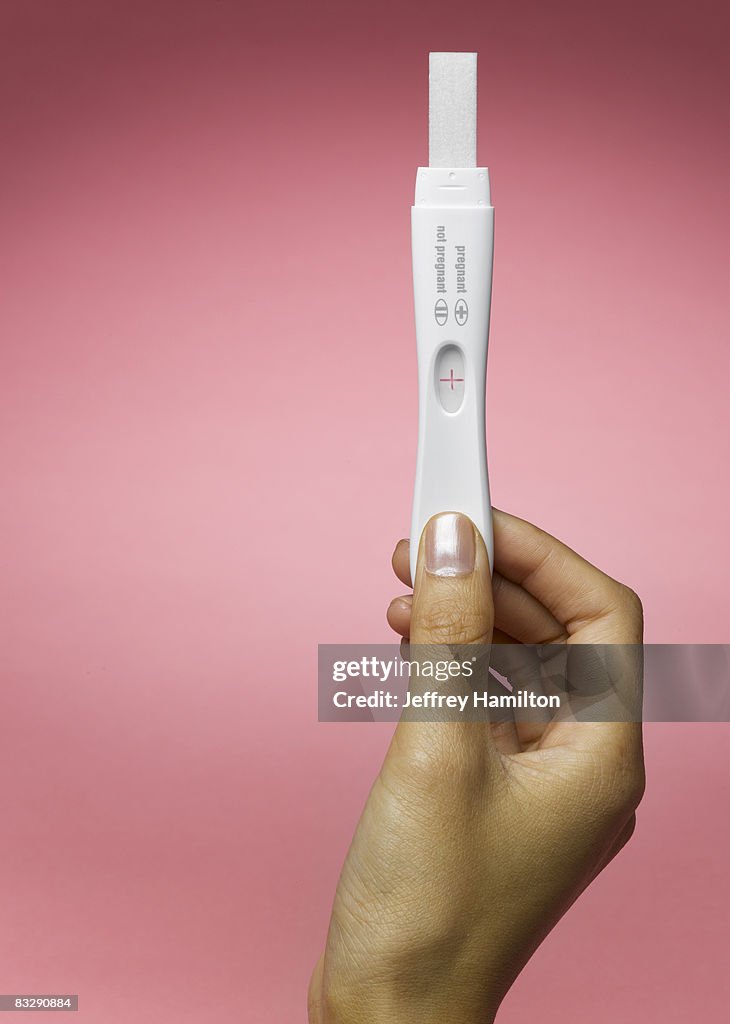 Woman's hand holding pregnancy test