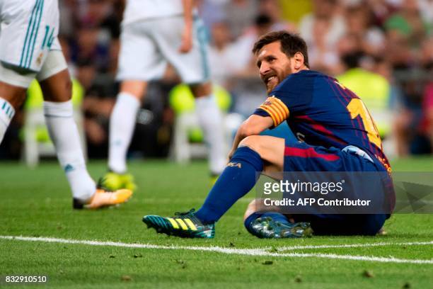 Barcelona's Argentinian forward Lionel Messi grimaces as he sits on the ground during the second leg of the Spanish Supercup football match Real...