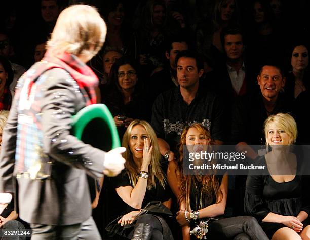 Singer/actress Miley Cyrus and mother Leticia Cyrus cheer for model Justin Gaston as he walks the runway at the Christian Audigier Presents American...