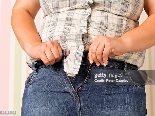 obese teenager doing up jeans - chubby girls stockfoto's en -beelden