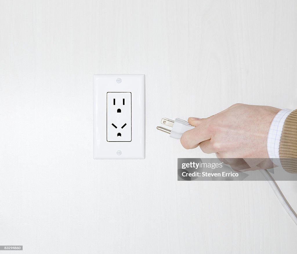 Electrical outlet making angry face as man tries t