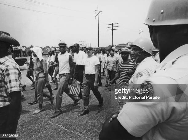 Police officers watch as civil rights campaigners take part in the Meredith Mississippi March near Jackson, Mississippi, June 1966. The march began...