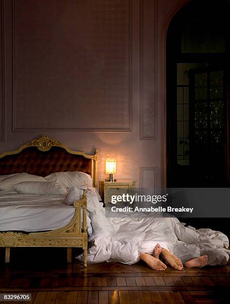 feet poking out under covers beside bed. - woman lying on stomach with feet up fotografías e imágenes de stock