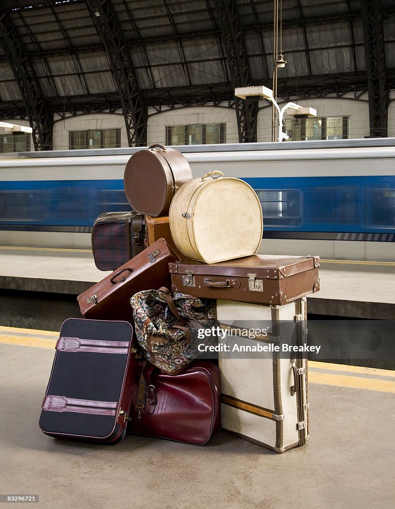 Large pile of luggage on train platform.