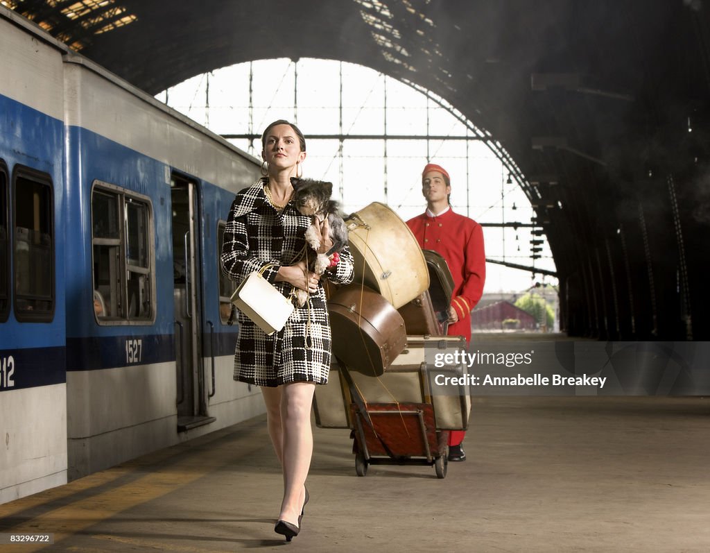 Woman with dog walking on train platform.
