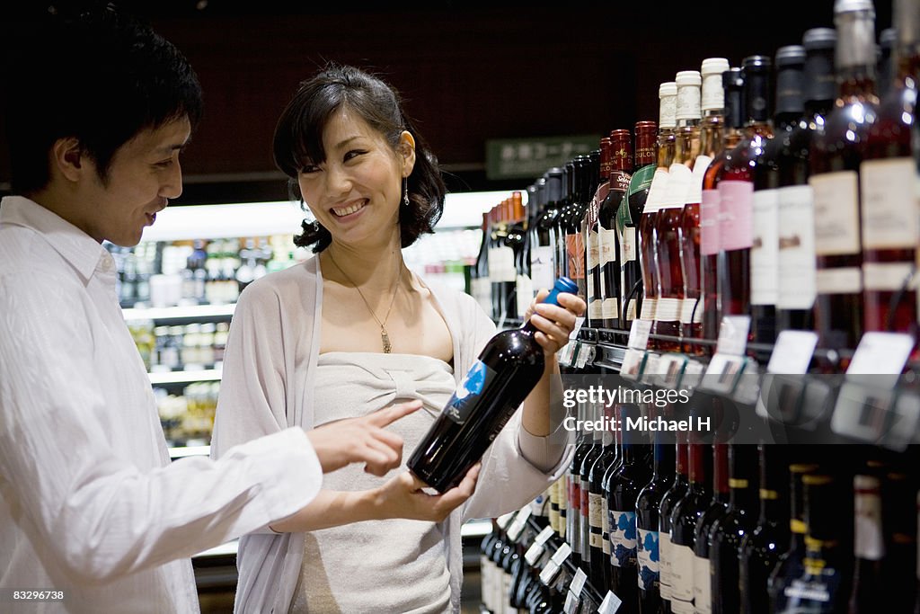 Young couple chooses wine in shop