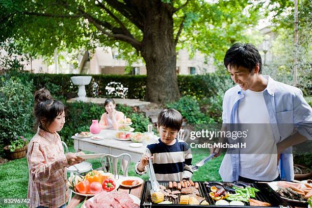 man and boy cooking barbecue for family - japanese girls hot fotografías e imágenes de stock