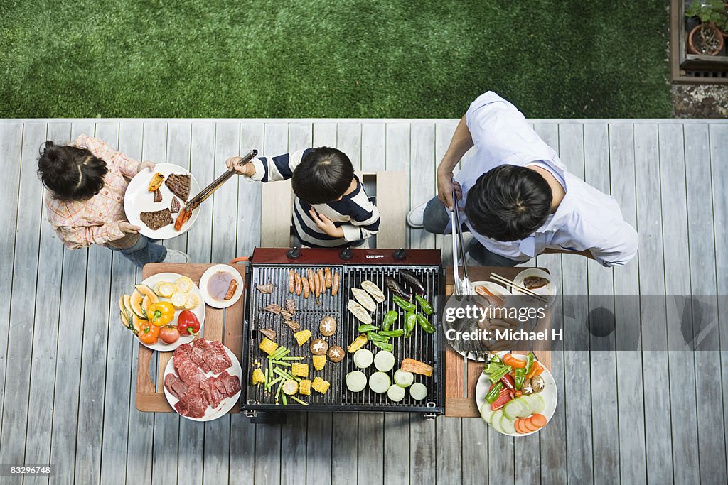 Man and boy cooking barbecue for family