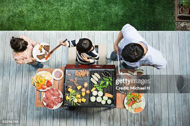 man and boy cooking barbecue for family - familie grillen stock-fotos und bilder